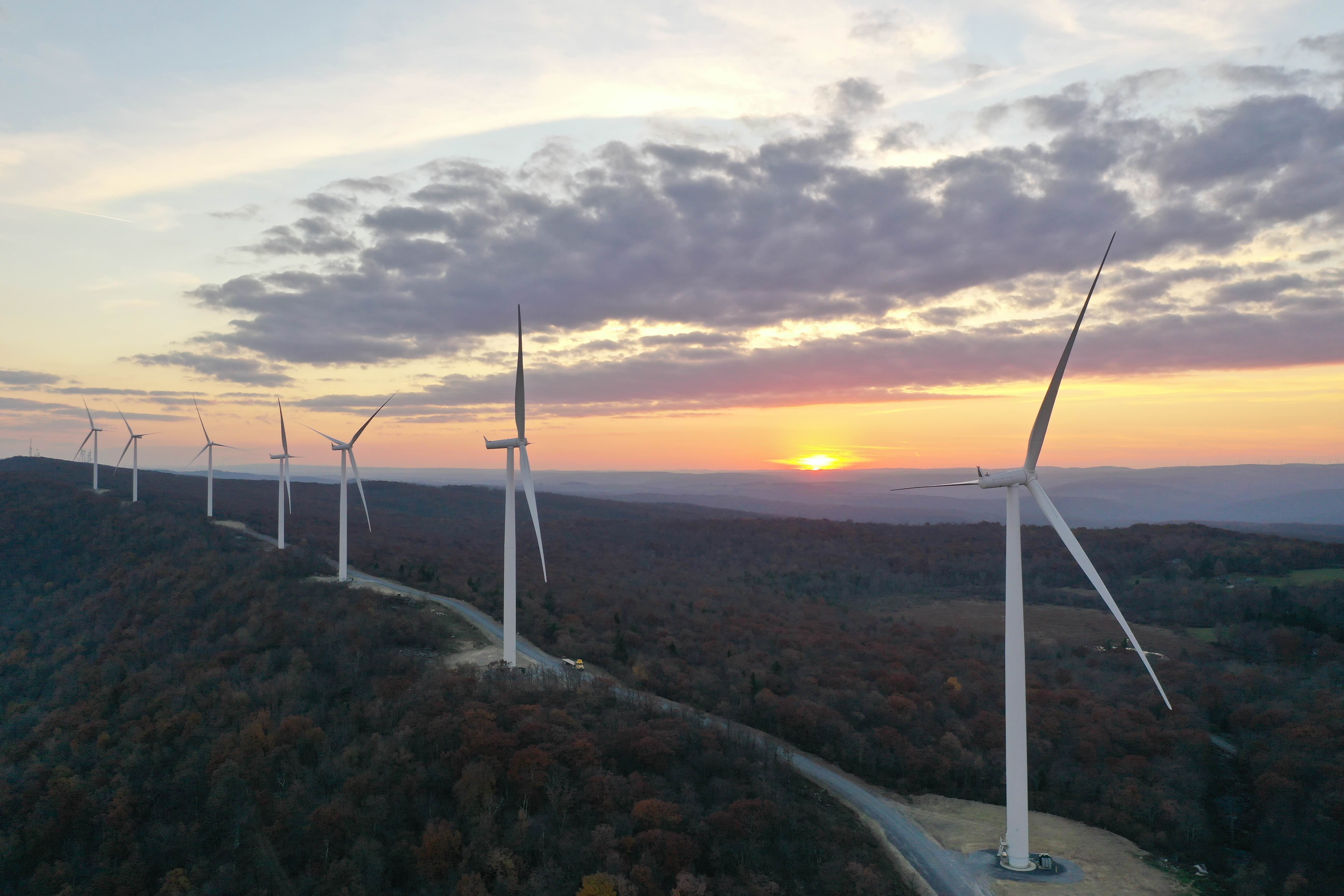Drone shot of a row of wind turbines set against a sunset,Drone shot of a row of wind turbines set against a sunset