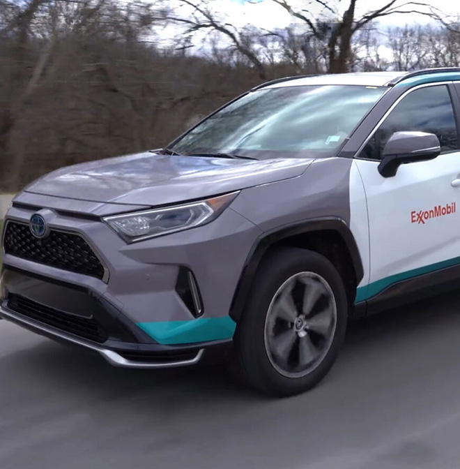 Toyota lower emission vehicle with ExxonMobil logo drives down a road